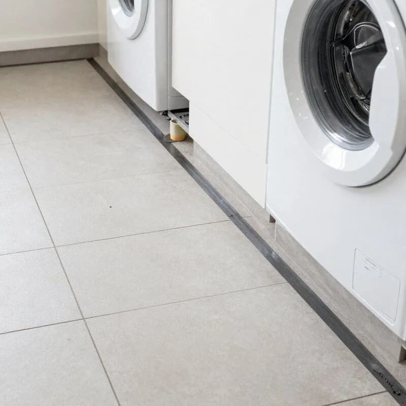 Laundry floor showing waterproofing membrane and correct drainage fall toward floor waste before tiling in a Melbourne home
