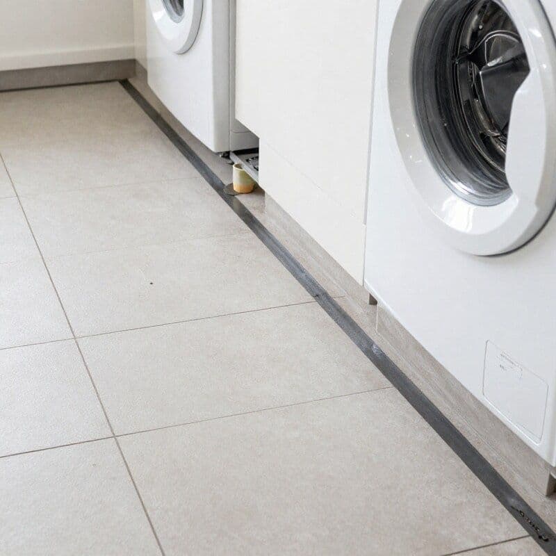 Laundry floor showing waterproofing membrane and correct drainage fall toward floor waste before tiling in a Melbourne home