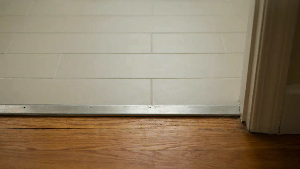 Close-up showing the height problem created by tiling over existing tiles at a Melbourne bathroom door frame junction requiring a threshold strip